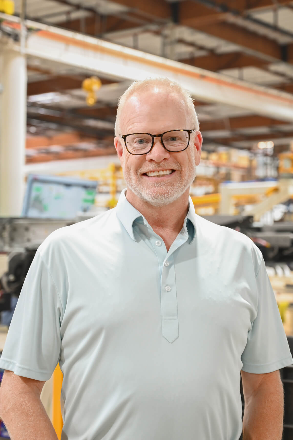 Executive portrait of Jay Klemp, VP of Sales standing inside the manufacturing facility, smiling toward the camera